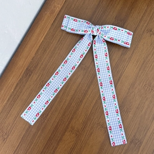 Détail de la barrette à nœud à carreaux bleus avec broderie florale rouge sur bois