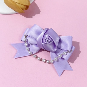 Detailed view of violet ribbon rose hair clip with white faux pearl tassels and satin texture