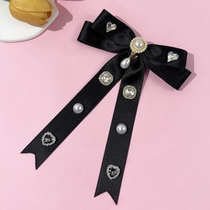 Detail einer luxuriösen Haarklammer aus schwarzem Satin mit Perlen und Strassherzen