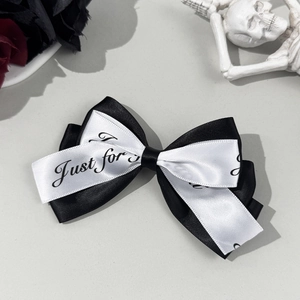 Detail of gothic style black and white satin ribbon bow hair clip with rose and skull decor