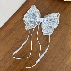Dettaglio del fermaglio a fiocco in pizzo azzurro con eleganti nappe di perle lucide
