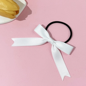 Detail of a white satin bow hair tie with fishtail ends on a high-elastic black band