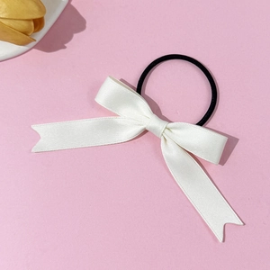 Detail of off-white satin bow hair tie with smooth silk texture and black elastic band