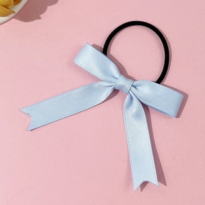 Detail view of a light blue satin bow hair tie with a black elastic band on pink background