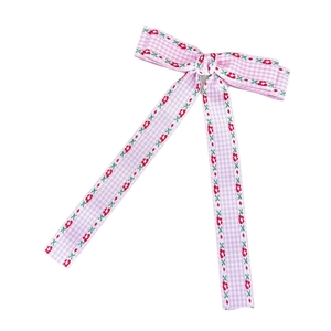 Nœud à cheveux rose à carreaux avec imprimé floral et longs rubans sur fond blanc
