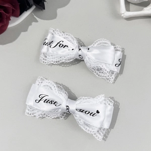 Dettaglio fermagli per capelli con fiocchi di pizzo bianco e scritta 'Just for you' Y2K