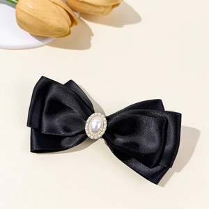 Detail einer schwarzen Satin-Schleife Haarspange mit großer Perle und funkelnden Kristallen