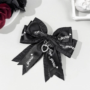 Detail of a black Lolita bow clip with frill edges, heart pendant, and for you lettering