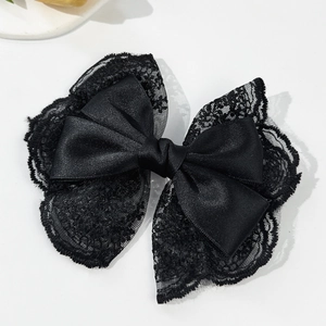 Close-up of elegant double-layered black lace and satin bow hair clip accessory
