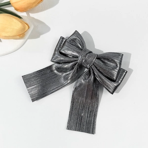 Detail view of silver pleated bow hair clip with shimmering fabric texture and double layer