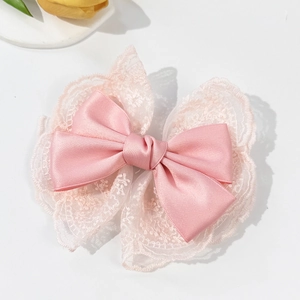 Detailed view of pink satin ribbon and white lace layers on a stylish bow hair clip