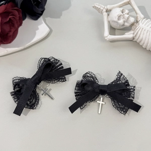 Close-up of black lace bow hair clips with silver cross pendants in a gothic aesthetic