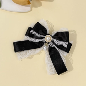 Detailed macro view of lace bow hair clip featuring satin ribbon and pearl pendant