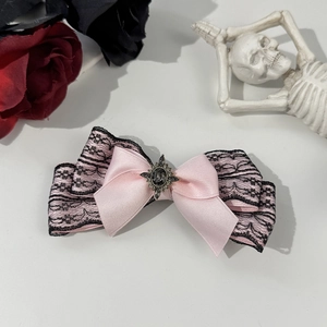Detail of gothic Lolita bow hair clip with black lace, pink satin, and vintage grey gemstone
