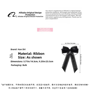Detail view of black ribbon bow hair clip showing silver chains and heart pendant