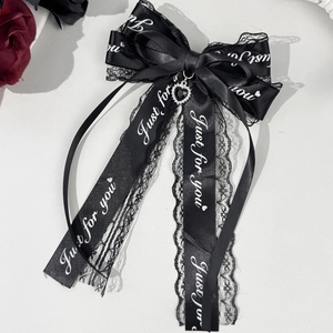 Détail d'un nœud papillon en dentelle noire avec pendentif cœur et lettrage brodé