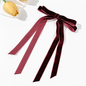 Dettaglio del fiocco per capelli in velluto bordeaux con lunghi nastri e tessuto elegante