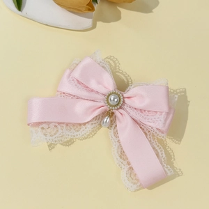 Detail of pink satin bow hair clip with white lace trim and pearl pendant drop