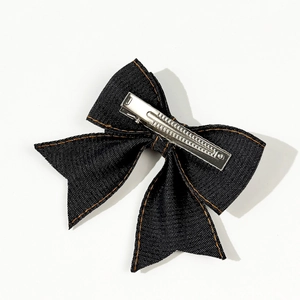 Denim bow hair clip in dark blue fabric with orange stitching and silver duckbill clip