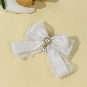 Detailed close-up of white lace bow hair clip with elegant pearl pendant and gold inlay