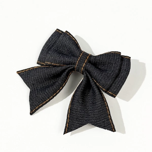 Close-up of dark blue denim bow hair clip with orange contrast stitching details