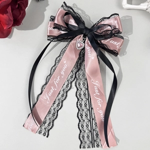 Détail du nœud à cheveux en satin rose et dentelle noire avec bijou cœur et ruban