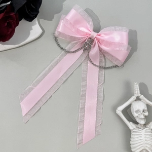 Detail of pink silk ribbon bow hair clip with silver heart cross and hanging chain