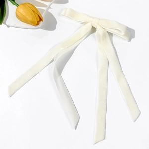 Dettaglio di un elegante fiocco per capelli in velluto bianco con lunghi nastri su sfondo