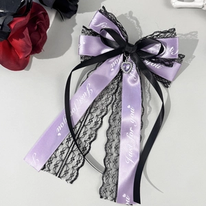 Détail du nœud à cheveux en satin violet et dentelle noire avec gemme cœur et pompons