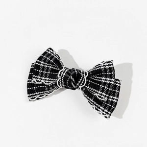 Detail of black and white checkered bow hair clip with white wavy stitching on tweed fabric