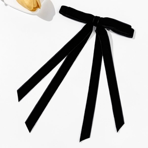 Dettaglio dell'elegante fiocco per capelli in velluto nero con lunghi nastri su bianco