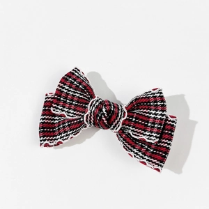 Close-up of a plaid bow hair clip with white lace trim and intricate tweed fabric texture