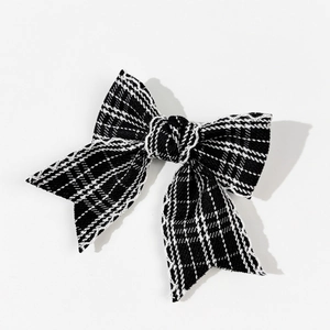 Detail of checkered bow hair clip featuring classic black and white plaid woven texture