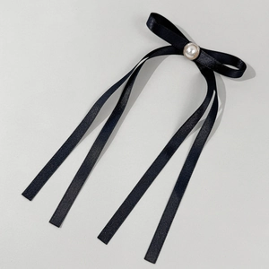 Dettaglio di elegante fermaglio in raso nero con doppi strati e una perla centrale