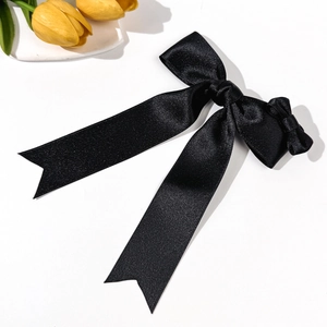 Detail of black satin bow hair clip with long ribbons on a white background