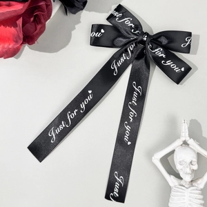 Détail d'un nœud papillon en satin noir avec imprimé Just For You et motif cœur
