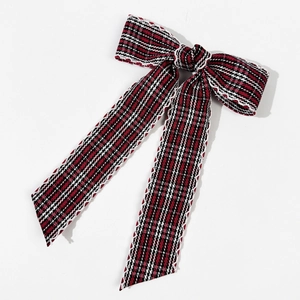 Detailed view of red and black plaid bow hairclip with delicate white lace trim