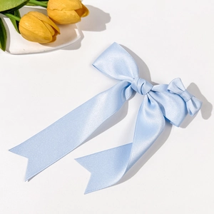 Detail of light blue silk bow hair clip with elegant long ribbons on a clean background