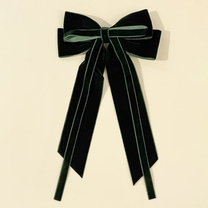Detail of dark green velvet bow hair clip with multi-layered ribbons and long streamers