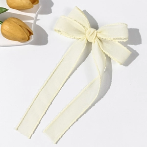 Detail of cream yellow organza bow hairclip with wave edges and elegant long ribbons