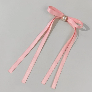 Dettaglio del fiocco in raso rosa con perla centrale ed eleganti nastri lunghi
