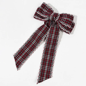 Close-up of retro plaid bow hair clip with textured weave and long ribbon streamers