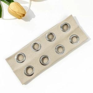 Détail d'un bandeau en tissu côtelé beige avec œillets argentés et décoration de tulipe