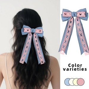 Détail de barrettes nœud en denim et dentelle avec longs rubans en divers coloris pastel