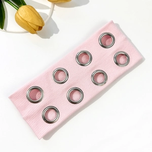Détail d'un bandeau côtelé rose avec des œillets métalliques argentés décoratifs