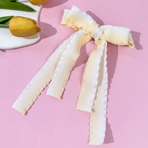 Detail of candy-colored gradient bow hair clip with ruffled edges and long flowing ribbons