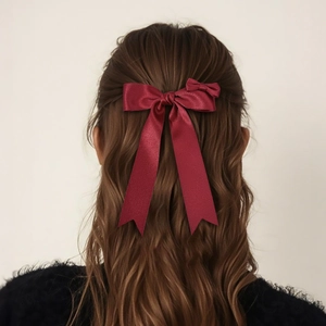 Elegant wine red satin ribbon bow hair clip shown on back of model's brown hair