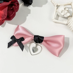 Detail of pink satin bow hair clip with black ribbons and silver heart cross pendant