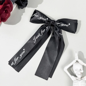 Detail of black satin bow hairclip featuring Just for you printed text in Gothic style