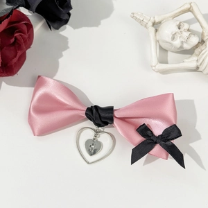 Detail of pink and black satin bow with silver heart cross pendant in gothic lolita style